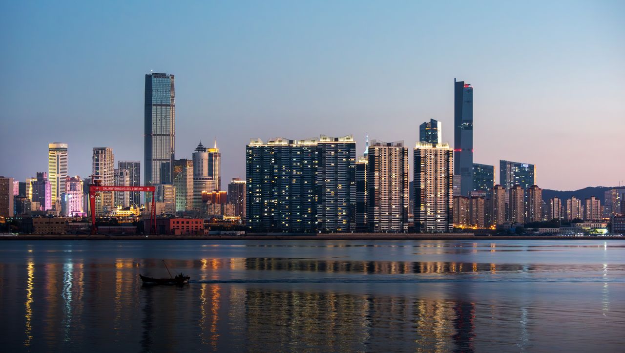 Modern city skyline reflected in water at twilight, showcasing skyscrapers.